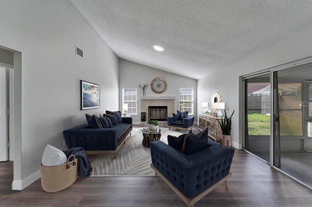 living room with lofted ceiling, visible vents, a tiled fireplace, wood finished floors, and baseboards