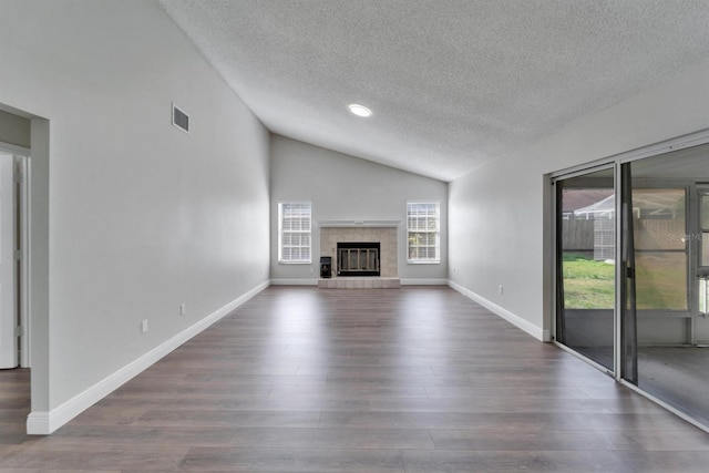 unfurnished living room with wood finished floors, visible vents, baseboards, vaulted ceiling, and a tiled fireplace