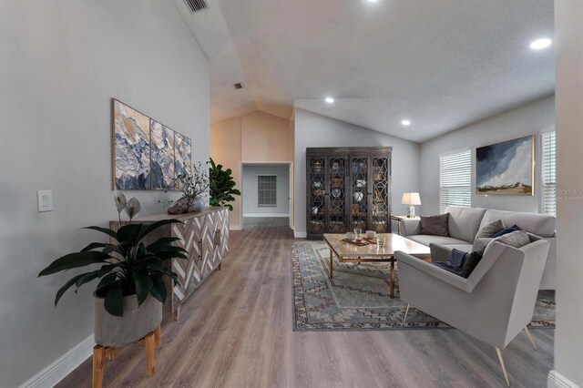 living area featuring visible vents, baseboards, lofted ceiling, wood finished floors, and recessed lighting