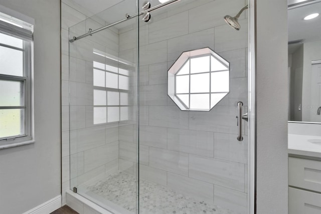 bathroom with baseboards, plenty of natural light, a shower stall, and vanity