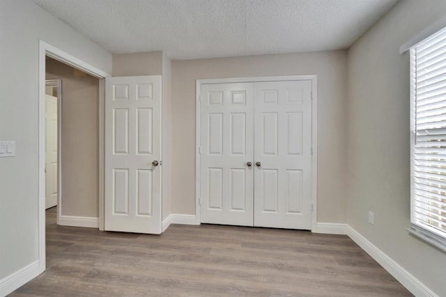 unfurnished bedroom with a closet, baseboards, and wood finished floors