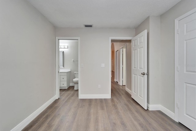 unfurnished bedroom with arched walkways, visible vents, baseboards, and wood finished floors