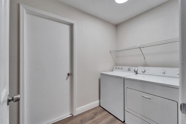 clothes washing area with baseboards, laundry area, light wood finished floors, and washer and dryer