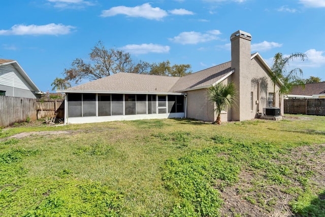 back of property featuring central AC unit, a sunroom, a fenced backyard, a yard, and stucco siding