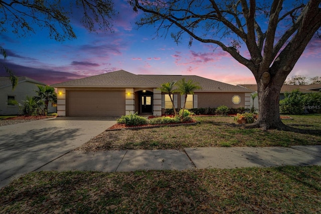 view of front of house featuring a garage, concrete driveway, and stucco siding