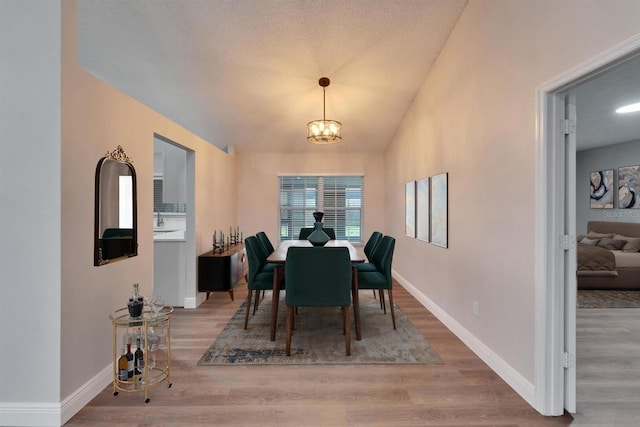 dining room with baseboards, vaulted ceiling, and wood finished floors