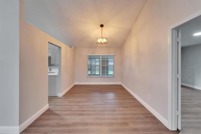 interior space with lofted ceiling, a notable chandelier, baseboards, and wood finished floors