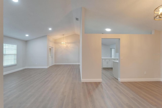 unfurnished living room featuring baseboards, vaulted ceiling, light wood-type flooring, a chandelier, and recessed lighting