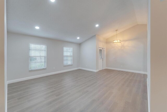 empty room with vaulted ceiling, light wood finished floors, recessed lighting, and baseboards