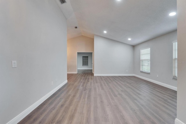 unfurnished living room featuring lofted ceiling, visible vents, baseboards, and wood finished floors