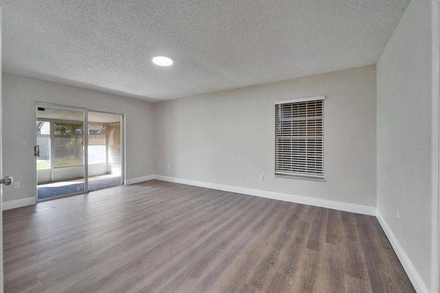 spare room featuring a textured ceiling, dark wood finished floors, and baseboards