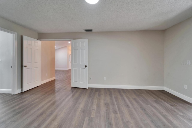 unfurnished bedroom with dark wood-style flooring, visible vents, and baseboards