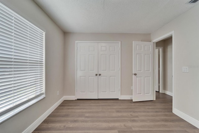 unfurnished bedroom with a closet, baseboards, and wood finished floors