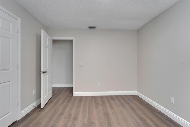 unfurnished room with baseboards, a textured ceiling, visible vents, and wood finished floors