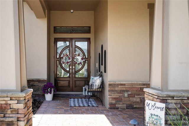 entrance to property featuring stone siding, brick siding, stucco siding, and french doors