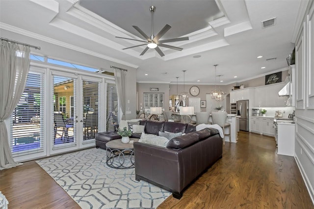 living room with visible vents, a raised ceiling, dark wood-style flooring, and ornamental molding