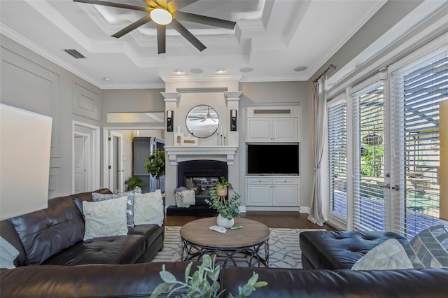 living room with a tray ceiling, a fireplace, visible vents, and crown molding