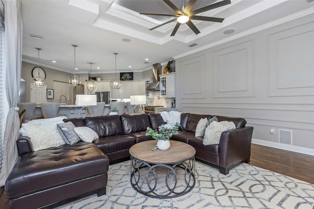 living area featuring a decorative wall, recessed lighting, visible vents, ornamental molding, and light wood finished floors