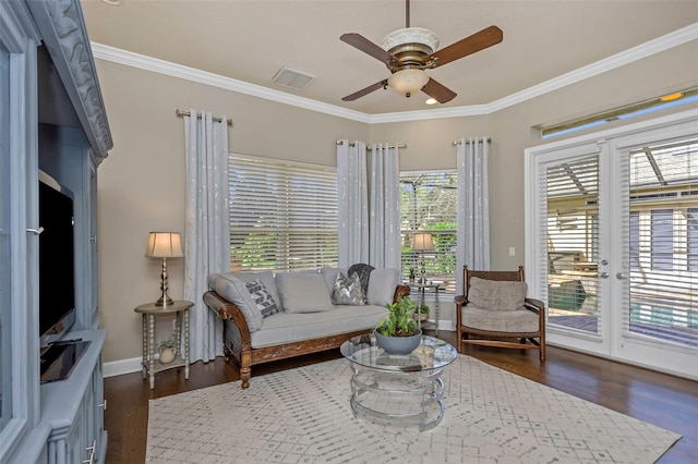 living room featuring ceiling fan, visible vents, baseboards, dark wood-style floors, and crown molding