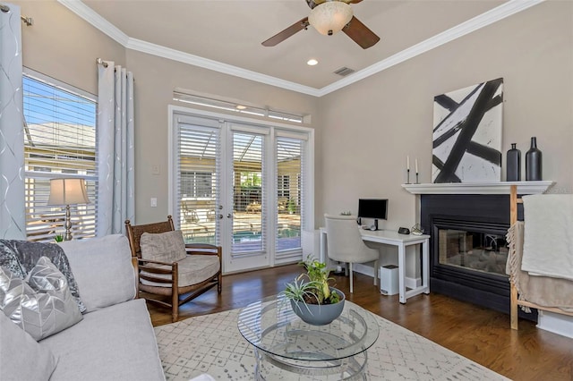 living room with wood finished floors, ornamental molding, a glass covered fireplace, and a wealth of natural light