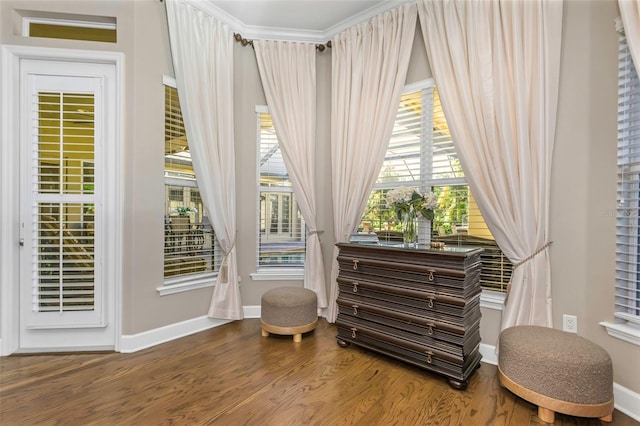 living area with ornamental molding, wood finished floors, and baseboards