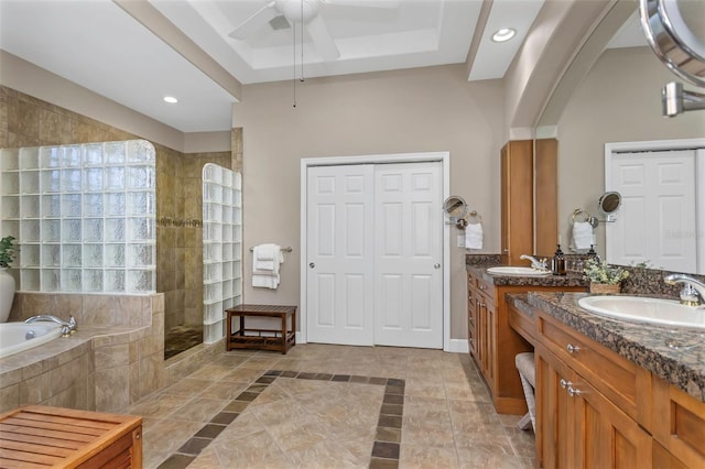 bathroom with a walk in shower, a tray ceiling, a sink, and a bath