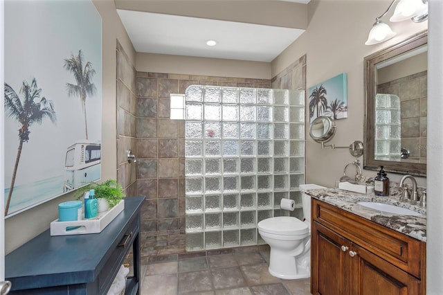 bathroom featuring toilet, walk in shower, and vanity