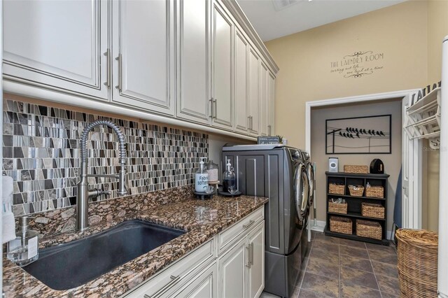 washroom featuring cabinet space, baseboards, washer and clothes dryer, and a sink