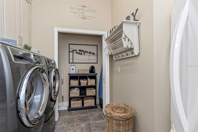 laundry area featuring dark tile patterned floors, washer and clothes dryer, and cabinet space