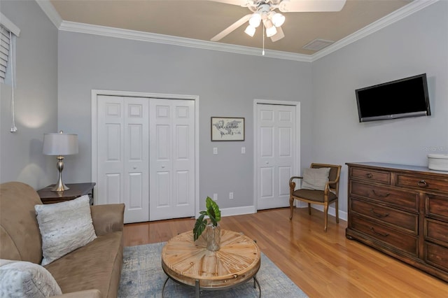 living room featuring ornamental molding, baseboards, light wood finished floors, and a ceiling fan