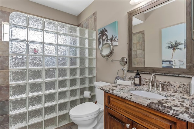 bathroom featuring toilet, a walk in shower, and vanity