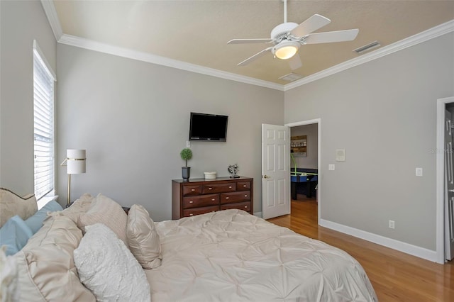 bedroom with visible vents, baseboards, a ceiling fan, wood finished floors, and crown molding