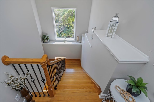 stairway with wood finished floors and baseboards