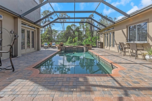 view of pool with a lanai, a pool with connected hot tub, outdoor dry bar, french doors, and a patio area