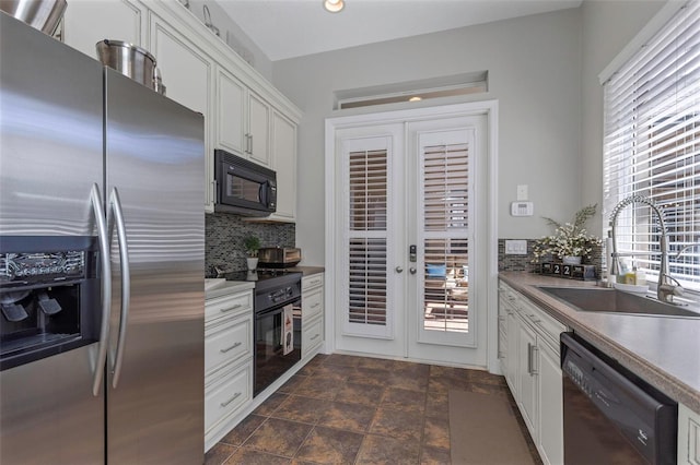 kitchen with a sink, white cabinetry, french doors, decorative backsplash, and black appliances