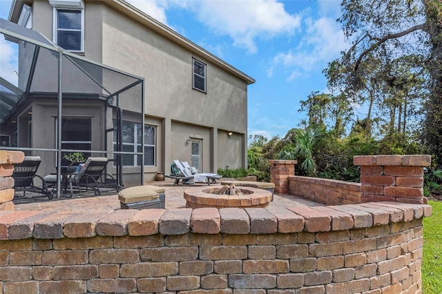 rear view of house with glass enclosure, a patio, and stucco siding