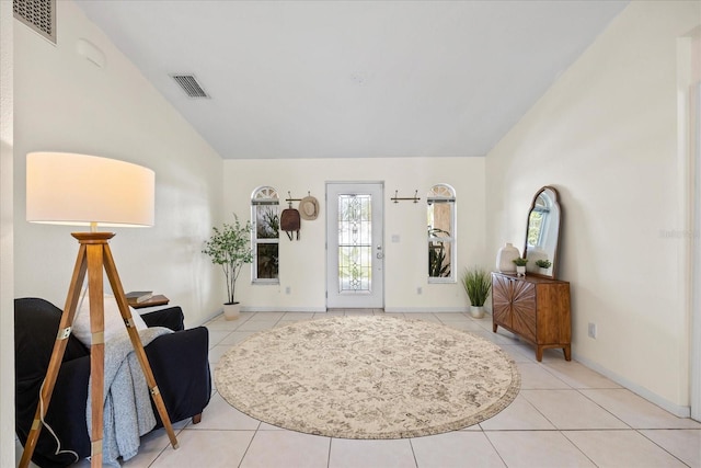 foyer with lofted ceiling, light tile patterned floors, baseboards, and visible vents