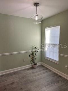 unfurnished room with baseboards and wood finished floors