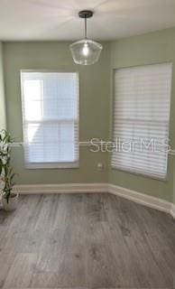 unfurnished dining area with baseboards and wood finished floors