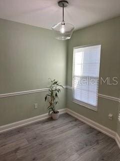 spare room with baseboards and wood finished floors