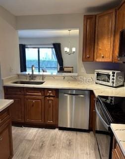 kitchen featuring light wood finished floors, light countertops, black electric range oven, stainless steel dishwasher, and a sink