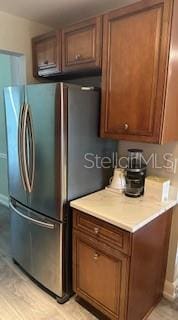 kitchen featuring brown cabinetry, freestanding refrigerator, and light countertops