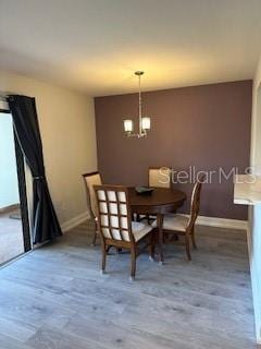 dining space featuring an inviting chandelier, baseboards, and wood finished floors