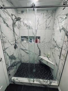 bathroom featuring a marble finish shower