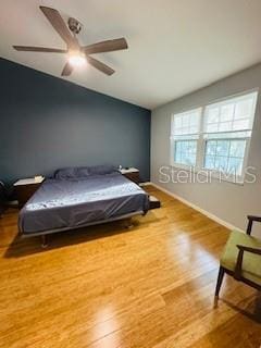 bedroom featuring vaulted ceiling, wood finished floors, a ceiling fan, and baseboards