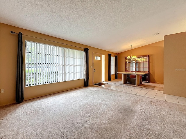 unfurnished living room with light tile patterned floors, visible vents, light colored carpet, an inviting chandelier, and vaulted ceiling