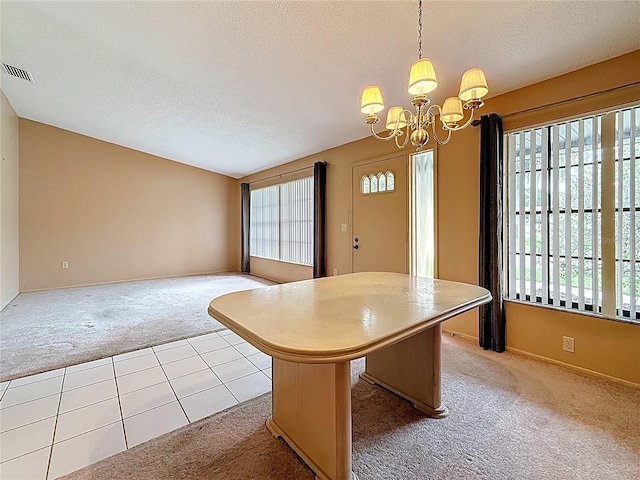 unfurnished dining area with carpet floors, an inviting chandelier, visible vents, and a textured ceiling