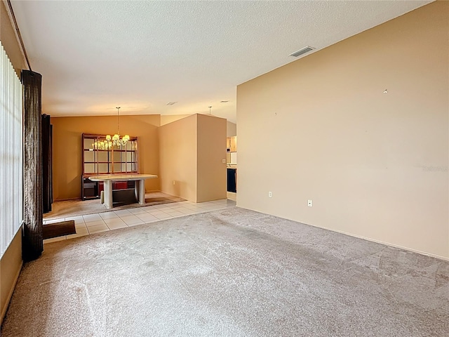 unfurnished living room with light tile patterned floors, visible vents, light colored carpet, vaulted ceiling, and a textured ceiling