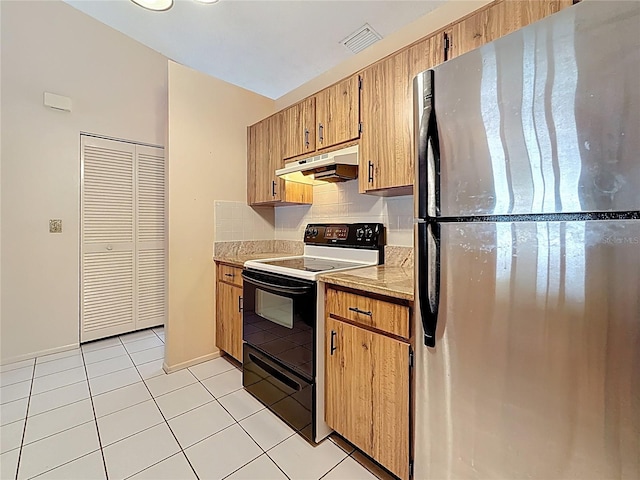 kitchen with light tile patterned floors, decorative backsplash, electric stove, freestanding refrigerator, and under cabinet range hood