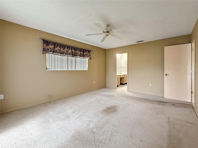 unfurnished room with a ceiling fan, light colored carpet, visible vents, and a textured ceiling